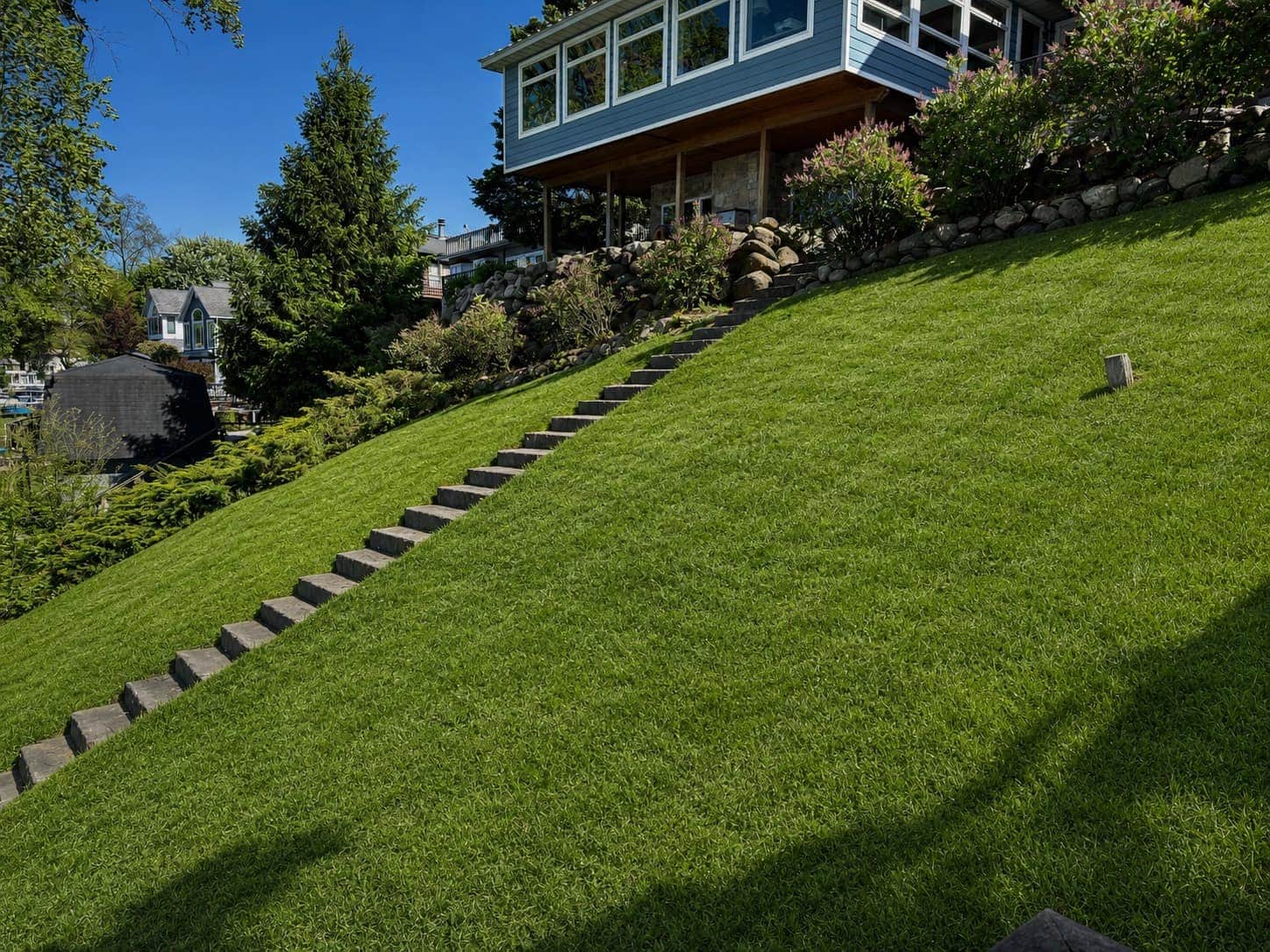 Dramatic hillside lawn with stone steps leading up to a Southwest Michigan lake house