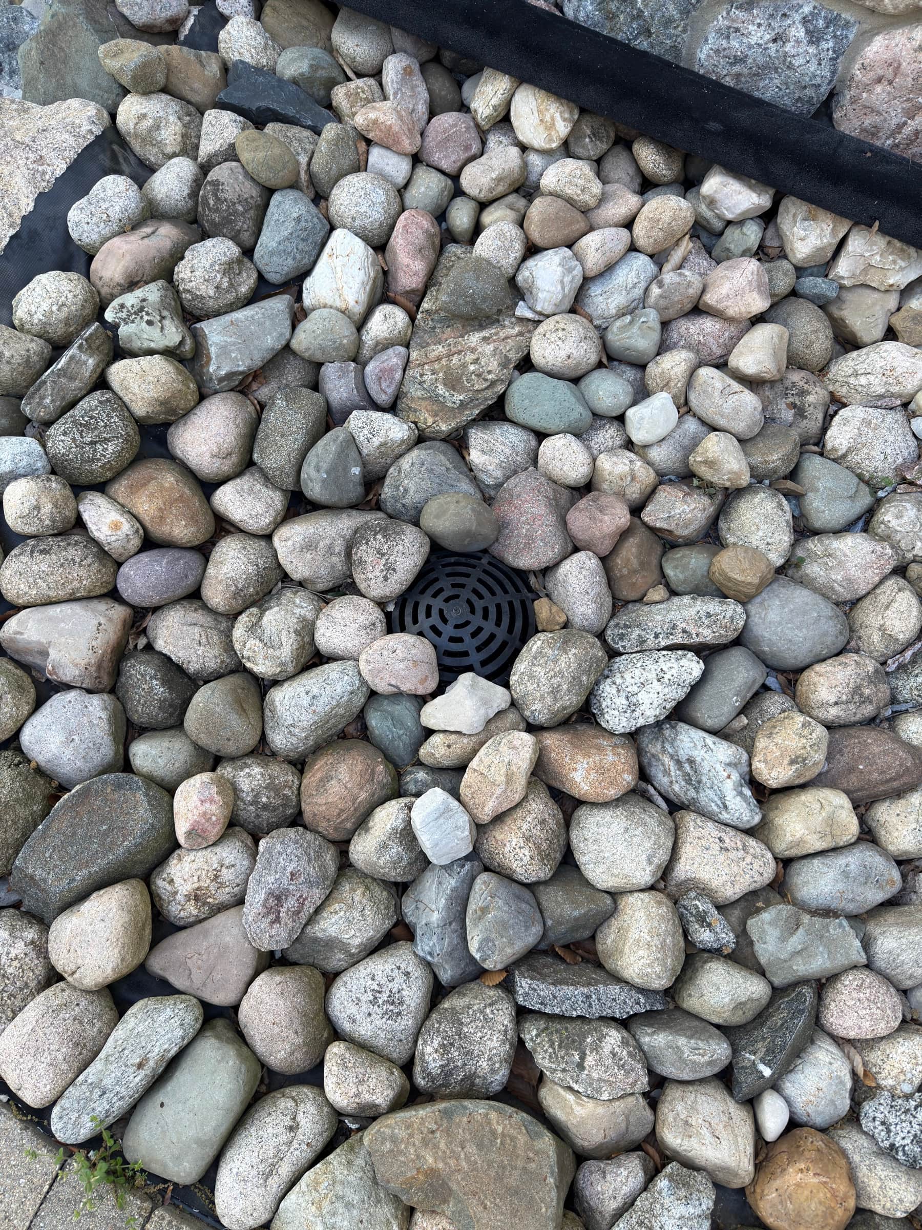 French drain concealed beneath river rock, Southwest Michigan drainage installation