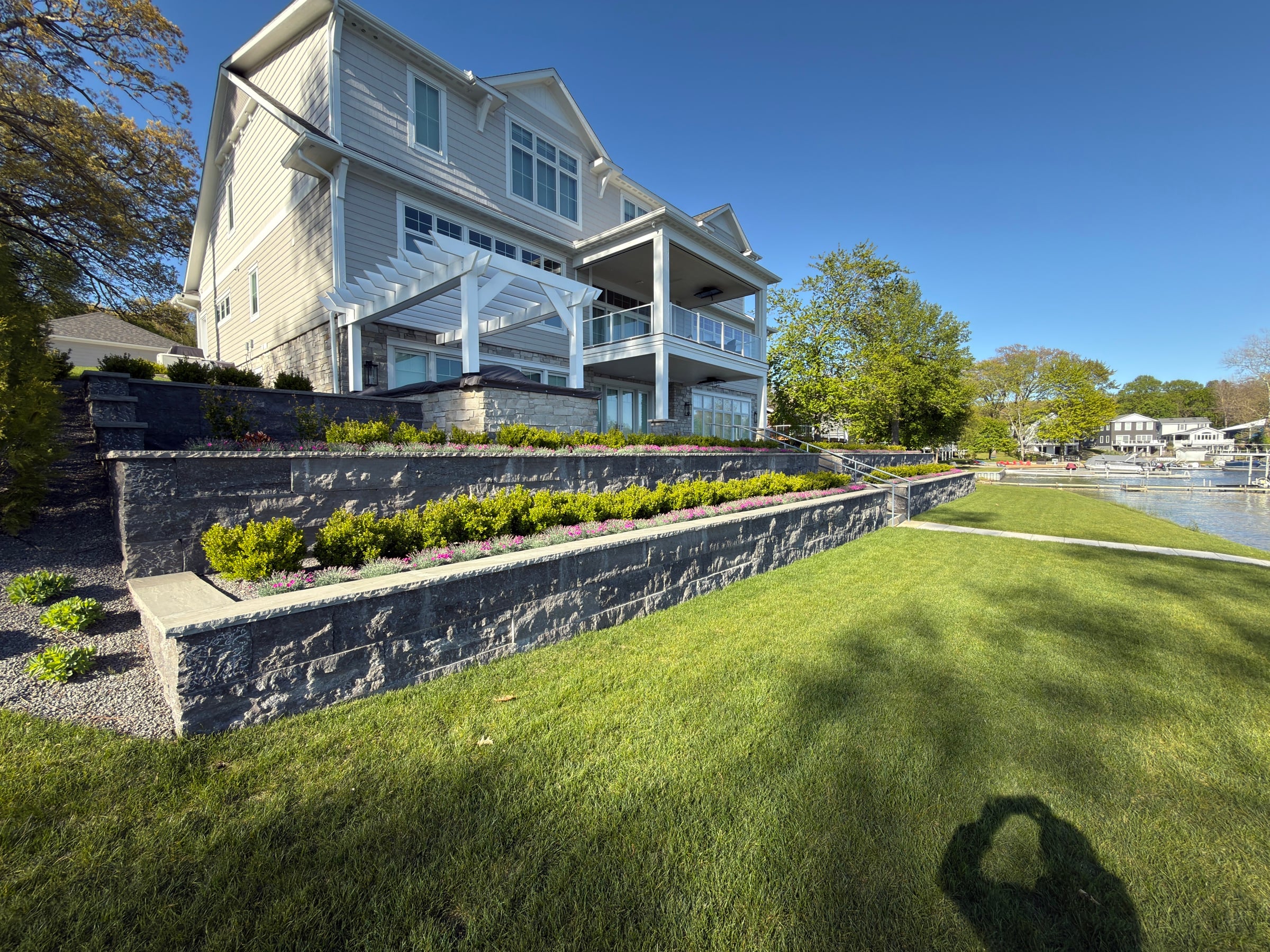 Tiered stone retaining walls with pergola and lakefront property built by MTL Landscaping