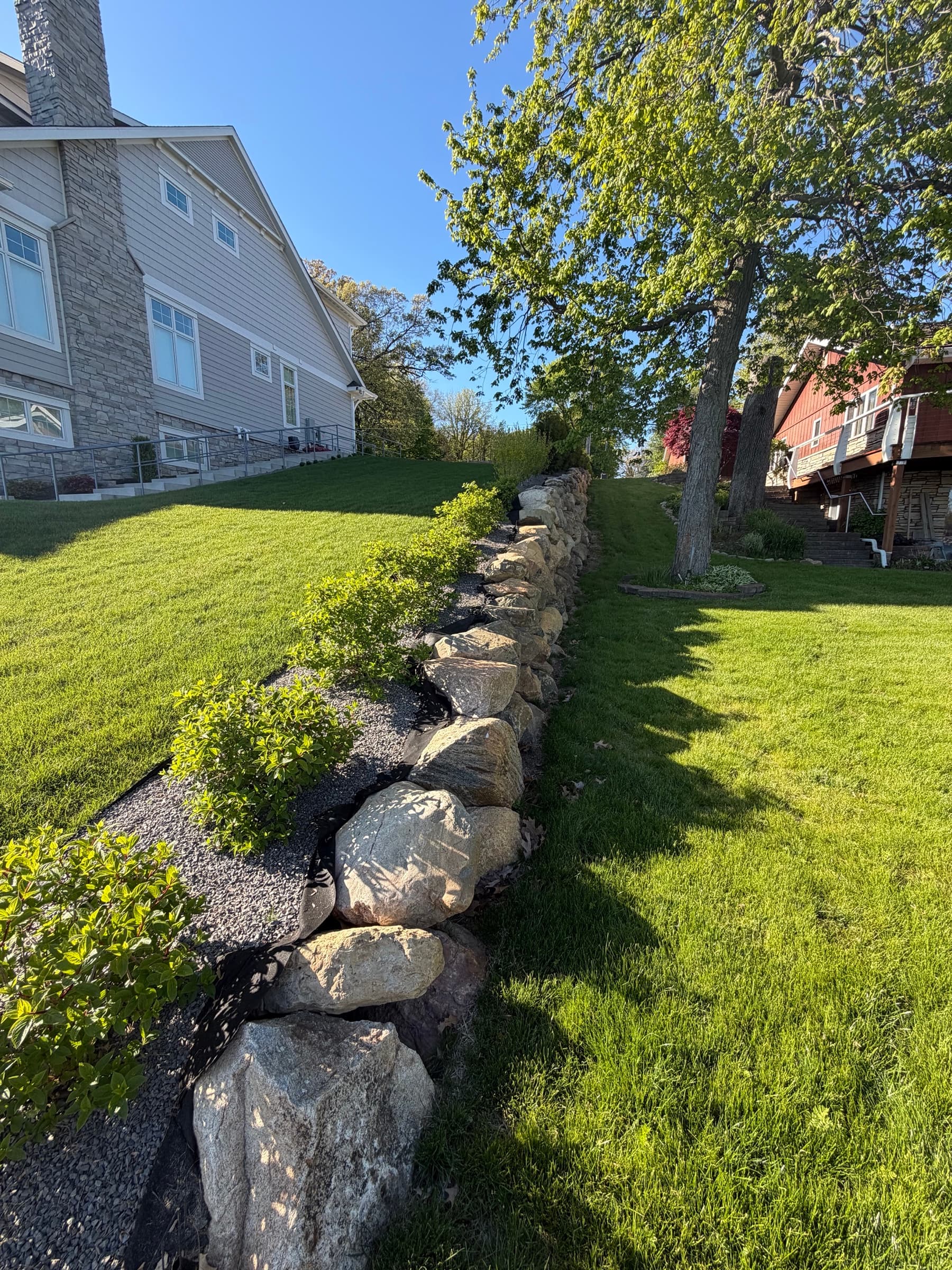 Natural boulder retaining wall with arborvitae plantings, Southwest Michigan lakefront